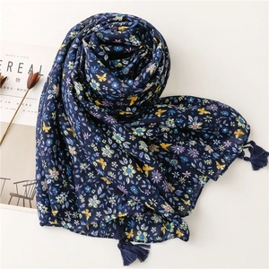 Detail of dark blue linen scarf with floral butterfly patterns and fringe tassels