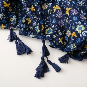 Detailed macro shot of dark blue floral scarf fabric featuring fringe and butterfly patterns