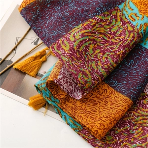 Vue détaillée d'une écharpe à motifs abstraits colorés avec pompons jaunes