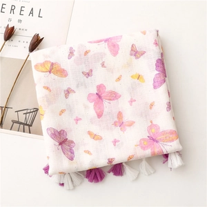 Detailed close-up of white linen texture scarf with pink butterfly prints and tassels