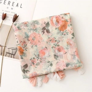 Detail of floral print scarf with soft cotton-linen texture and pink tassel trim