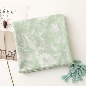 Detail of light green floral cotton linen scarf featuring soft tassels and art print