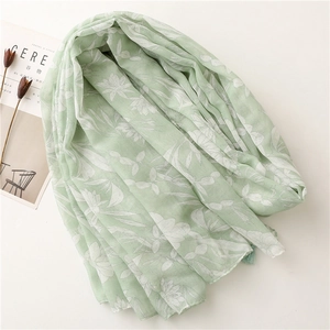 Light green cotton-linen scarf with white floral prints and delicate tassels on white