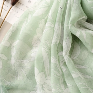 Detailed macro view of green linen cotton scarf with white floral prints and fringe