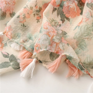 Detail of floral linen scarf showing peach rose print and handmade tassels on edges