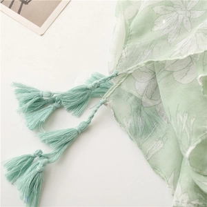 Detail of light green floral scarf with handcrafted tassels and soft texture