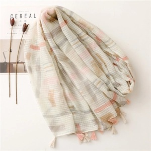Elegant beige plaid scarf with abstract patches and tassels next to a magazine