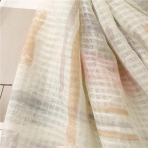 Detailed macro shot of creamy beige scarf showing fine linen texture and woven stripes