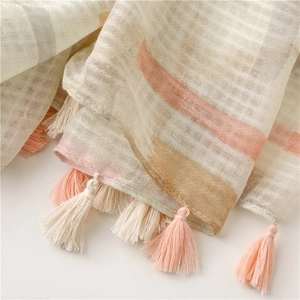 Close-up of cotton linen scarf texture featuring light pink watercolor print and handmade tassels