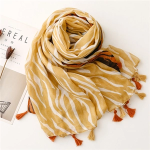 Détail d'une écharpe jaune à motif zébré avec des franges à côté d'un magazine