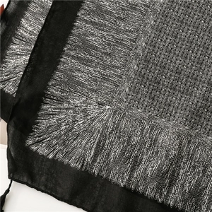 Gros plan d'une écharpe en coton-lin noir avec motifs abstraits blancs et détails à franges