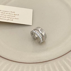 Macro detail of silver double-layer ear cuff with zircons and star engraving patterns