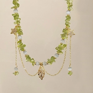 Green natural stone necklace with gold leaf pendant and pavé star charms on beige background