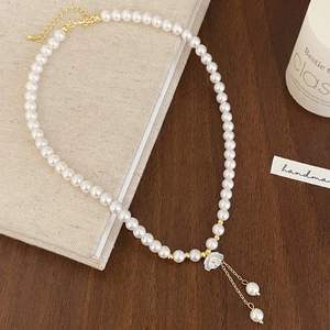 Collier élégant en perles d'eau douce avec pendentif fleur et pompon sur livre