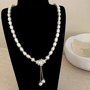 Détail d'un collier de perles d'eau douce avec fleur blanche et pampilles dorées