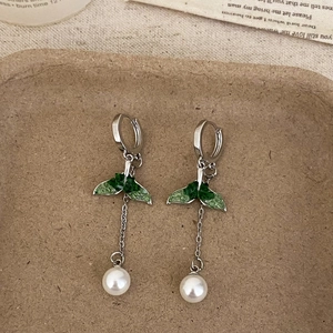 Detail of green butterfly wing earrings with white pearl drop on textured tray