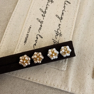 Elegant floral pearl stud earring set with zircons and gold alloy base on display