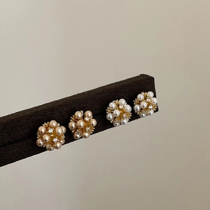 Macro shot of two pairs of gold-plated pearl flower stud earrings with zircon accents