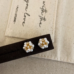Detail of cluster stud earrings featuring white pearls and tiny zircons in gold finish