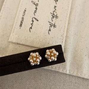 Macro detail of cluster pearl earrings with gold base and zircon centers on display