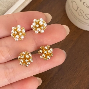 Close-up of gold cluster earrings with small white pearls and zircon crystal stones