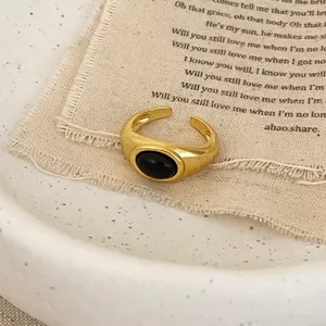Close-up of a vintage gold-plated ring featuring an oval black opal in a wide band setting