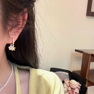 Détails de boucles d'oreilles marguerite en or avec cristaux portées par un mannequin