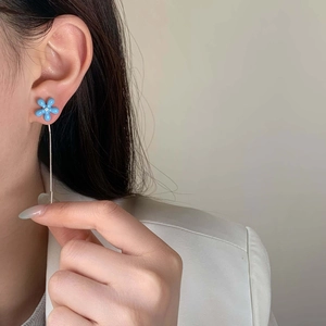 Detail of blue flower stud earrings with elegant long metal chain tassel on model