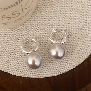 Elegant rose-tinted pearl drop earrings with silver hoops on minimalist linen background