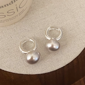 Macro detail of silver metal hoop earrings with elegant grey pearls on linen texture