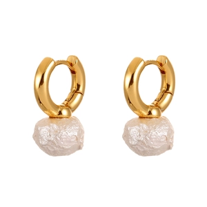 Macro view of polished gold hoop earrings featuring elegant baroque white pearls