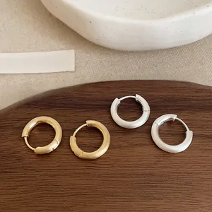 Macro view of gold and silver brushed hoop earrings on a minimalist wooden tray