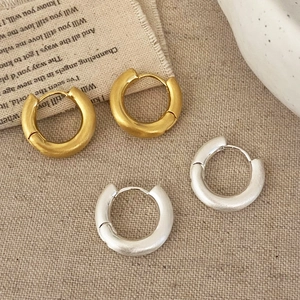 Detail of gold and silver brushed hoop earrings on beige textured background fabric