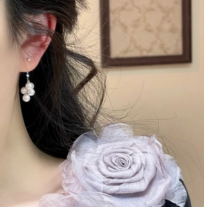 Detail of silk mauve rose brooch and clustered pearl earrings worn by a model