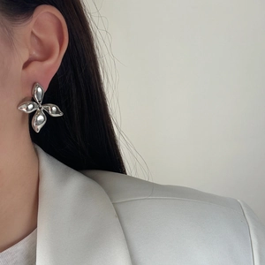 Close-up of a silver petal earring with a polished mirror finish on a female model