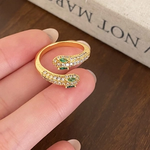 Golden snake open ring with white zircon paving and green gemstone eyes on hand