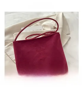 Détail du sac bandoulière en daim bordeaux avec lettrage embossé élégant
