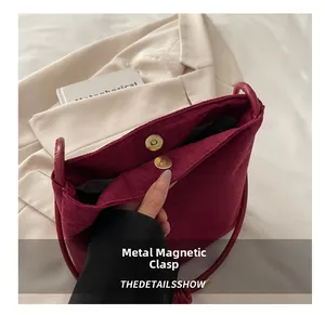 Détail du fermoir magnétique en métal et de la texture en daim du sac bandoulière bordeaux