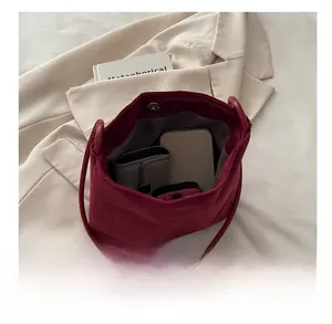 Détail de l'intérieur spacieux du sac en velours côtelé bordeaux avec accessoires