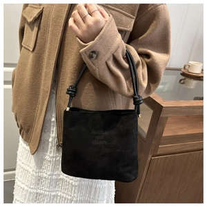 Gros plan détaillé d'un sac en daim noir avec bandoulière nouée et lettrage embossé