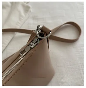 Detailed close-up of the smooth silver zipper and D-ring on the beige bucket bag