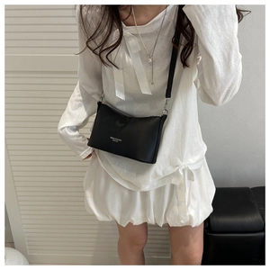 Detail view of a black fashion bucket bag with white slogan and silver metal hardware