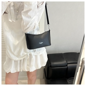 Détail du sac à bandoulière en cuir noir avec logo texte blanc sur le devant