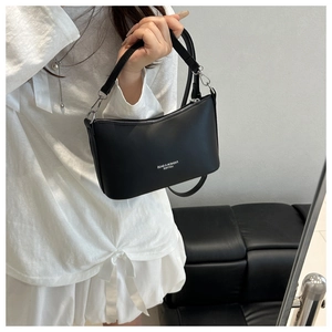 Détail du sac bandoulière en cuir noir avec fermeture éclair en métal et logo embossé
