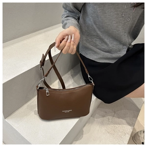 Détail du sac sous l'aisselle en cuir marron café avec ferrures argentées sur des marches