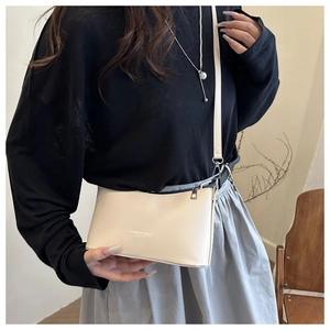 Détail d'un sac bandoulière beige avec texte Fashion & Bags et fermeture éclair métallique