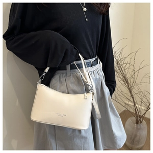 Sac à épaule chic en cuir crème avec fermeture éclair argentée et logo imprimé