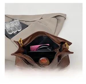 Top view of spacious brown cloud bag interior holding wallet, phone and cosmetics