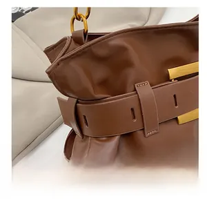 Close-up of dark brown soft leather bag featuring decorative strap and gold hardware