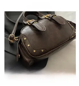 Detail of dark brown vintage bowling bag showing faux leather texture and gold rivets